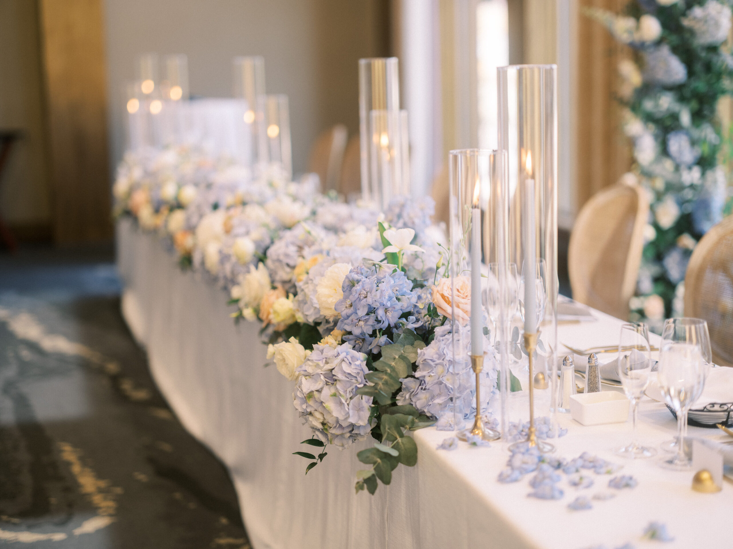 French Blue Parisian Wedding Inspiration, blue tapered candles wedding, gold cutlery, head table florals, bridal table flowers, hydrangea centrepieces, tall hydrangea centrepiece, blue ceremony arch, hydrangea ceremony arch, french wedding, light blue wedding, dusty blue florals, anemones, wedding floral inspo, blue wedding hydrangeas, nicole sarah
