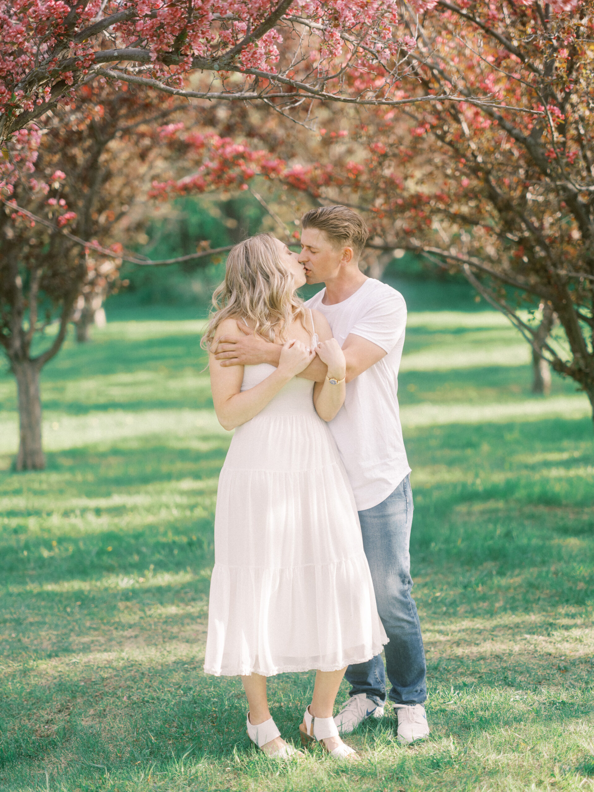 Cherry Blossom Spring Engagement Session, river engagement couple laughing, couple embracing, engagement pose sunset, sunset engagement photos, labrador retriever engagement photos, dog engagement session, puppy engagement session, alberta wedding photographers, alberta photographer, calgary wedding, calgary wedding photographer, spring engagement session, spring photos, nicole sarah, cherry blossom photos, cherry blossom engagement, wedding poses, white dress engagement, sundress white, engagement photos, bow river, puppy engagement photos, neutral engagement photos