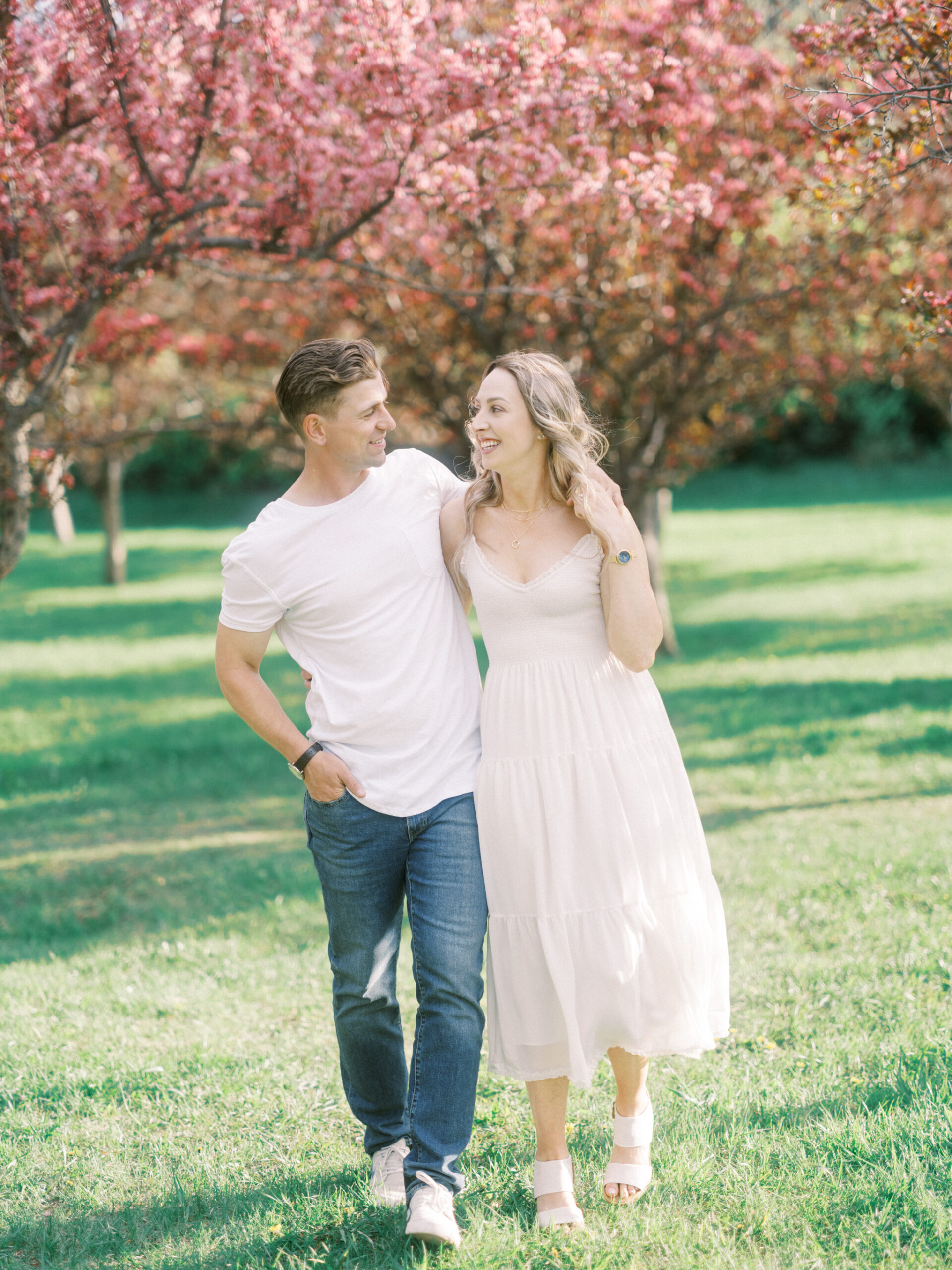 Cherry Blossom Spring Engagement Session, river engagement couple laughing, couple embracing, engagement pose sunset, sunset engagement photos, labrador retriever engagement photos, dog engagement session, puppy engagement session, alberta wedding photographers, alberta photographer, calgary wedding, calgary wedding photographer, spring engagement session, spring photos, nicole sarah, cherry blossom photos, cherry blossom engagement, wedding poses, white dress engagement, sundress white, engagement photos, bow river, puppy engagement photos, neutral engagement photos