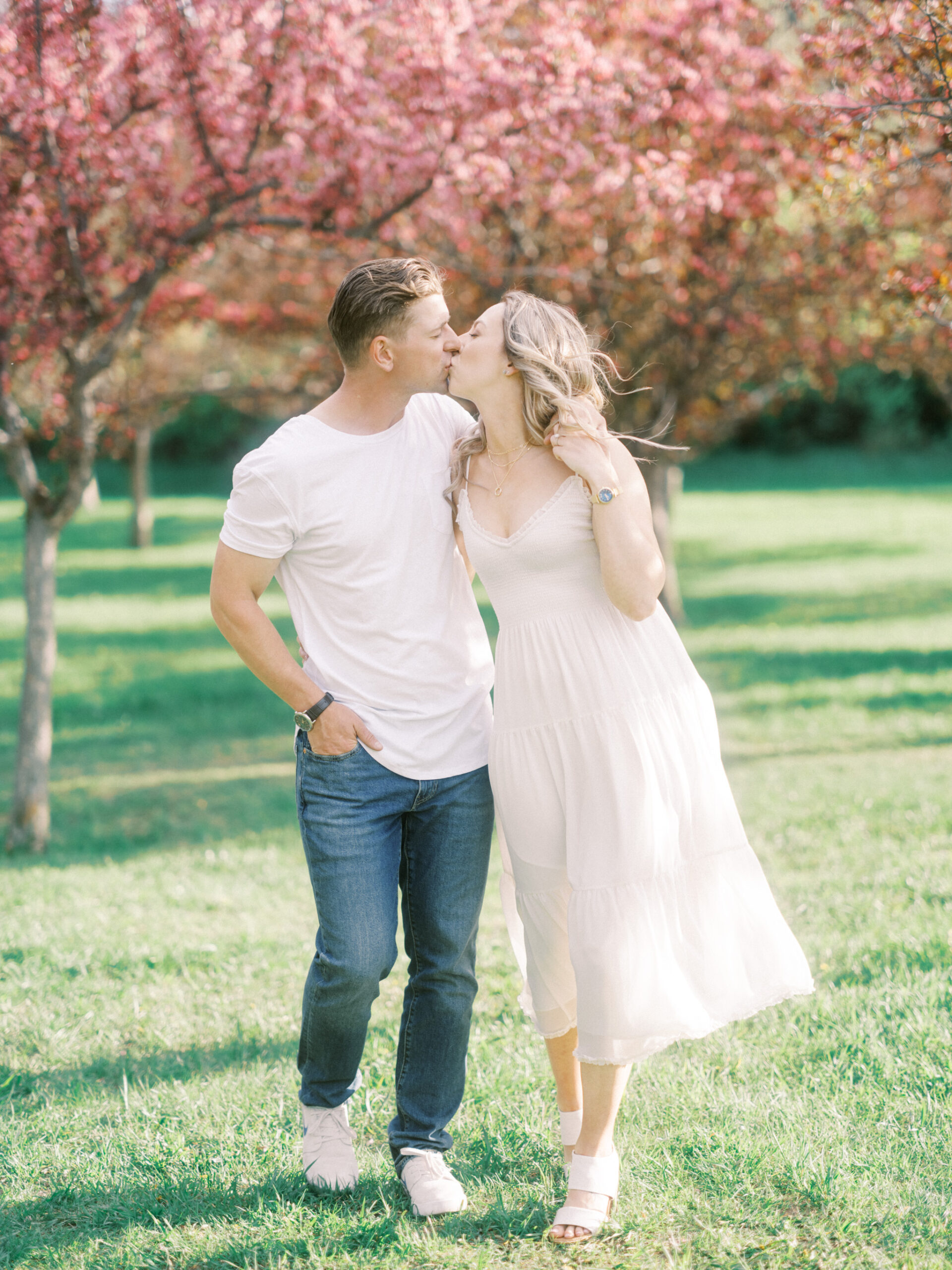 Cherry Blossom Spring Engagement Session, river engagement couple laughing, couple embracing, engagement pose sunset, sunset engagement photos, labrador retriever engagement photos, dog engagement session, puppy engagement session, alberta wedding photographers, alberta photographer, calgary wedding, calgary wedding photographer, spring engagement session, spring photos, nicole sarah, cherry blossom photos, cherry blossom engagement, wedding poses, white dress engagement, sundress white, engagement photos, bow river, puppy engagement photos, neutral engagement photos