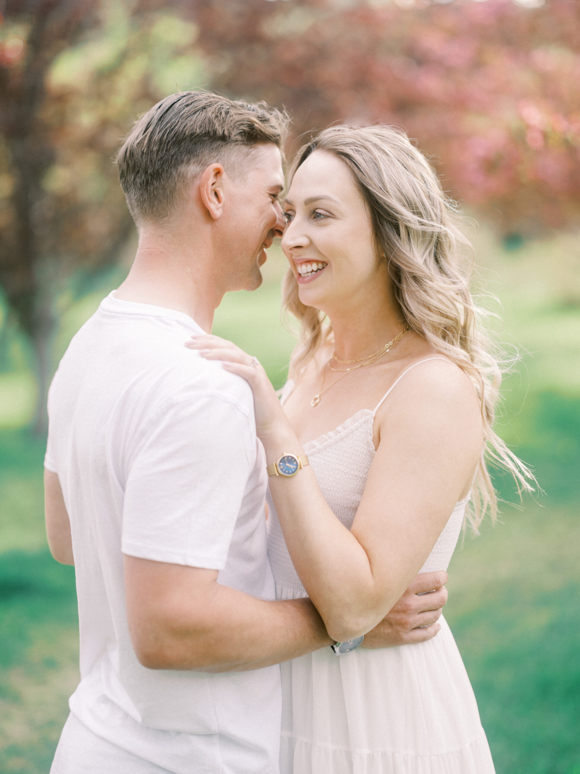 Cherry Blossom Spring Engagement Session, river engagement couple laughing, couple embracing, engagement pose sunset, sunset engagement photos, labrador retriever engagement photos, dog engagement session, puppy engagement session, alberta wedding photographers, alberta photographer, calgary wedding, calgary wedding photographer, spring engagement session, spring photos, nicole sarah, cherry blossom photos, cherry blossom engagement, wedding poses, white dress engagement, sundress white, engagement photos, bow river, puppy engagement photos, neutral engagement photos