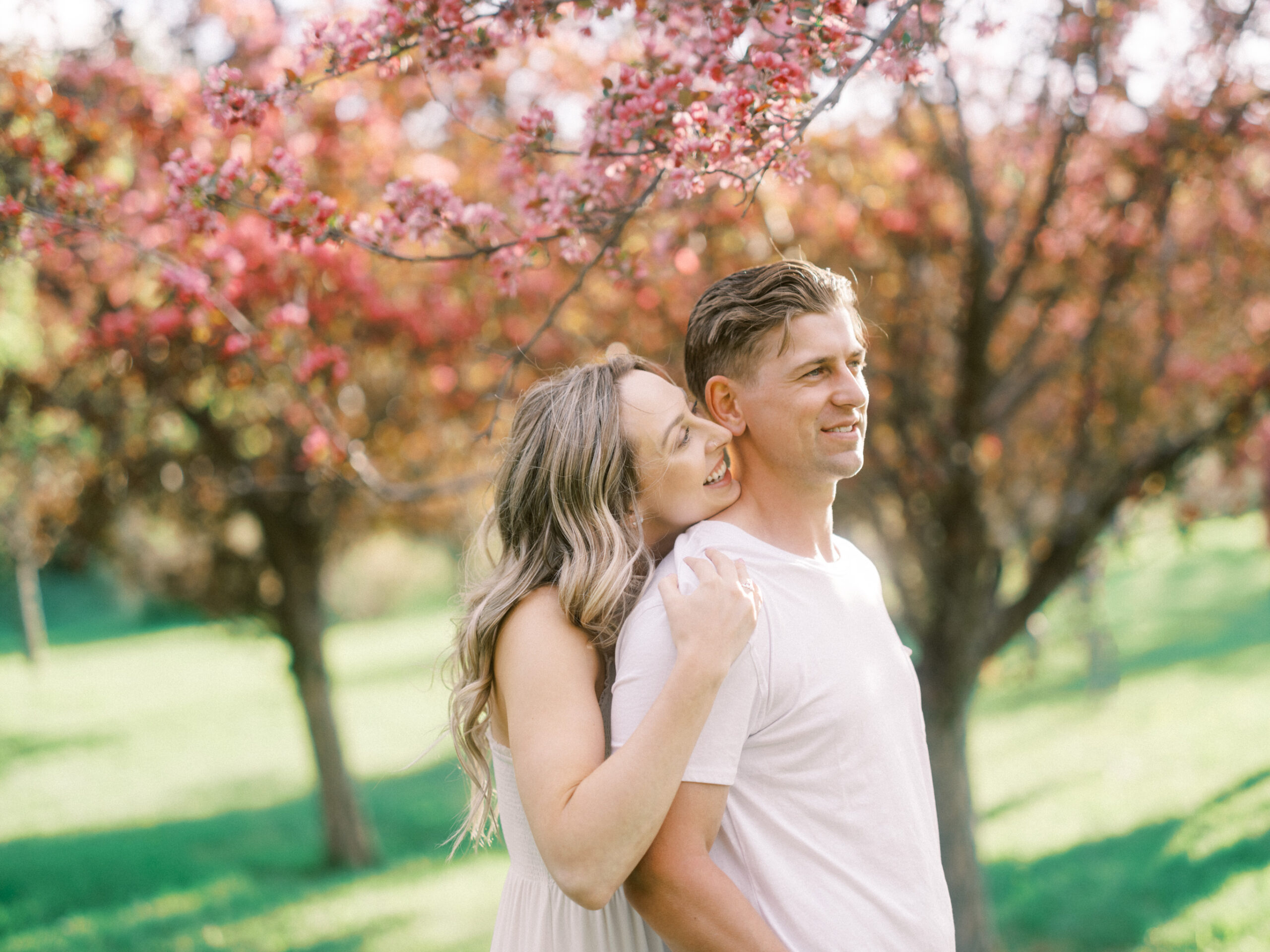 Cherry Blossom Spring Engagement Session, river engagement couple laughing, couple embracing, engagement pose sunset, sunset engagement photos, labrador retriever engagement photos, dog engagement session, puppy engagement session, alberta wedding photographers, alberta photographer, calgary wedding, calgary wedding photographer, spring engagement session, spring photos, nicole sarah, cherry blossom photos, cherry blossom engagement, wedding poses, white dress engagement, sundress white, engagement photos, bow river, puppy engagement photos, neutral engagement photos