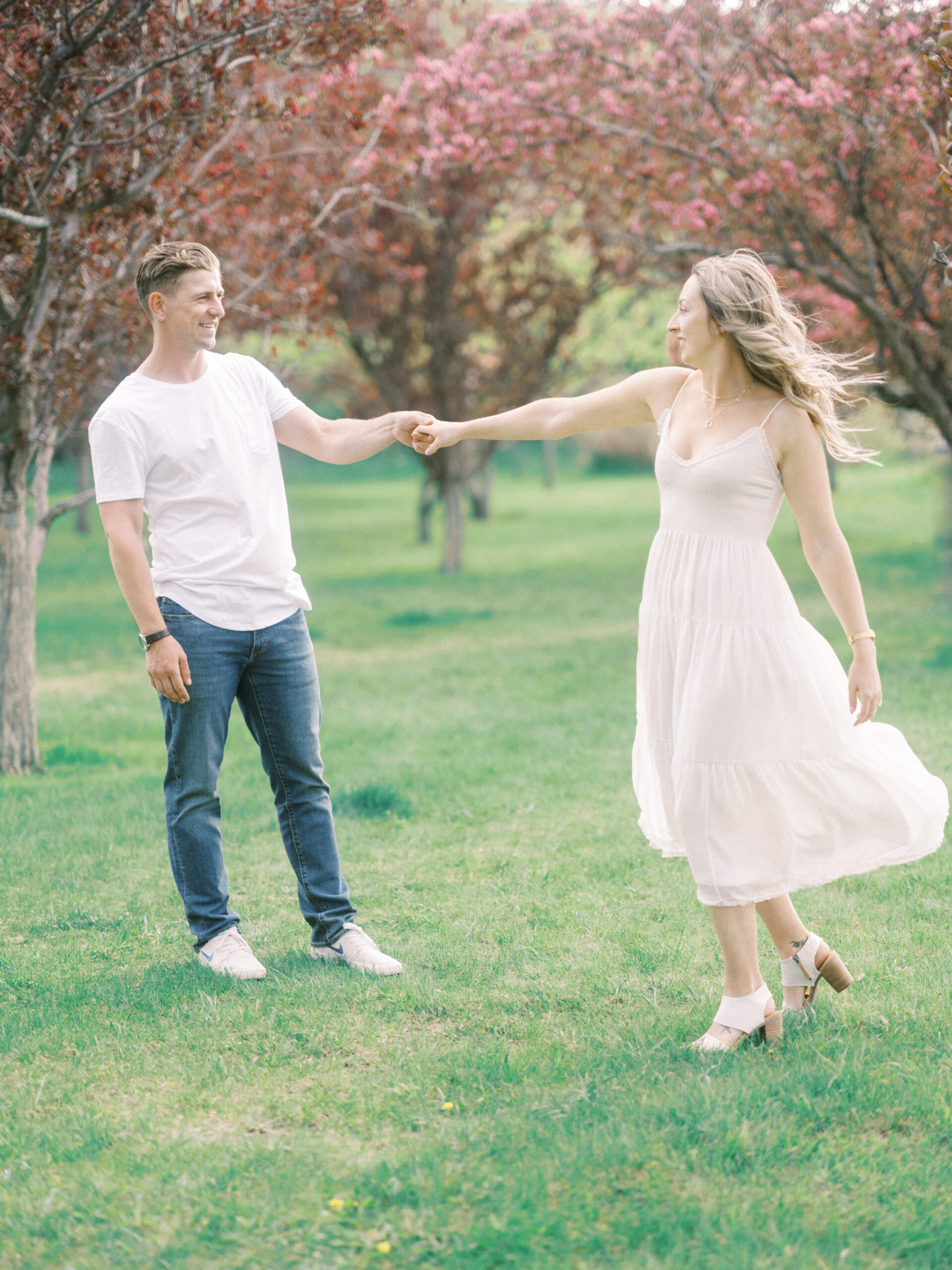 Cherry Blossom Spring Engagement Session, river engagement couple laughing, couple embracing, engagement pose sunset, sunset engagement photos, labrador retriever engagement photos, dog engagement session, puppy engagement session, alberta wedding photographers, alberta photographer, calgary wedding, calgary wedding photographer, spring engagement session, spring photos, nicole sarah, cherry blossom photos, cherry blossom engagement, wedding poses, white dress engagement, sundress white, engagement photos, bow river, puppy engagement photos, neutral engagement photos