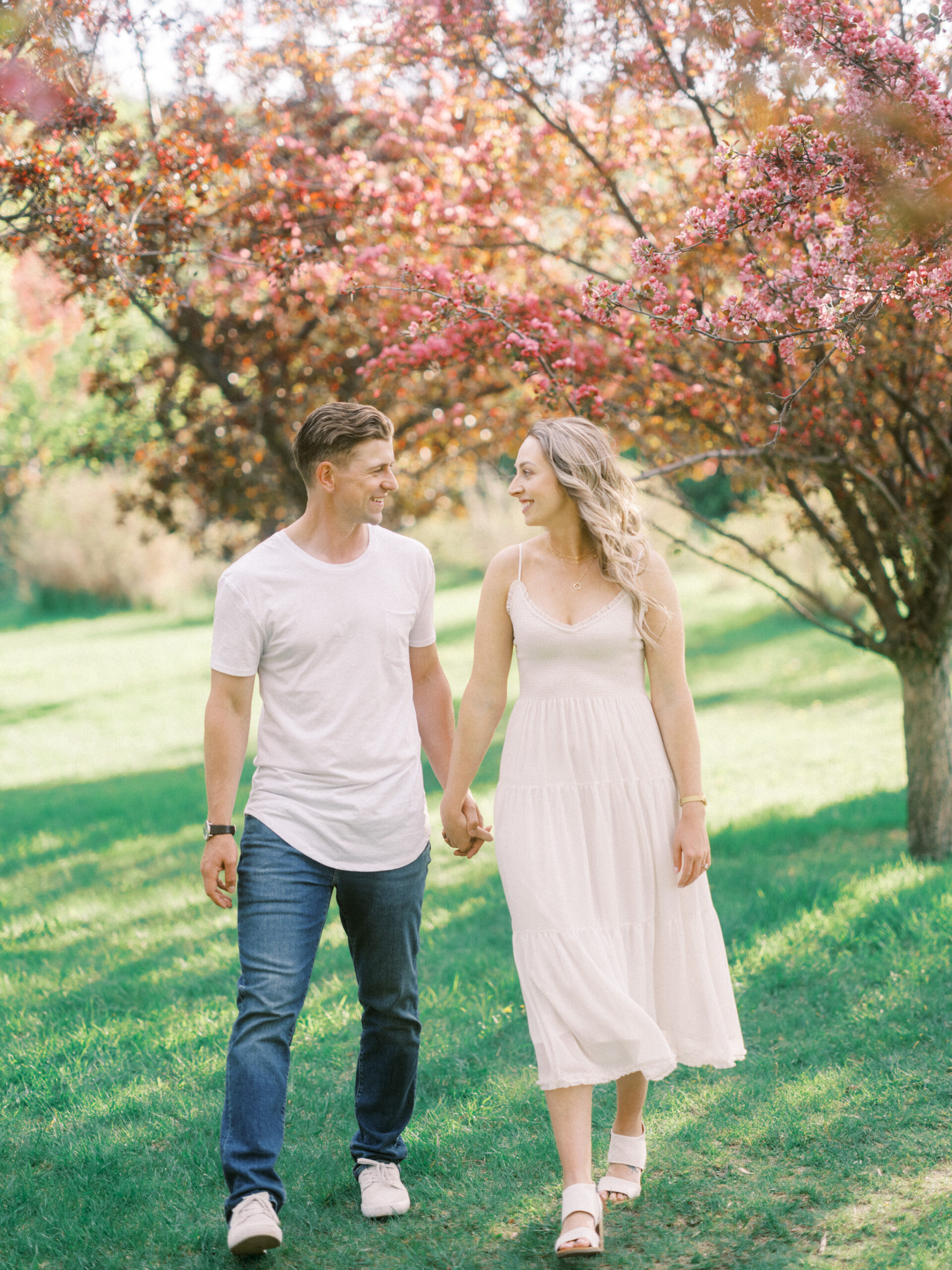 Cherry Blossom Spring Engagement Session, river engagement couple laughing, couple embracing, engagement pose sunset, sunset engagement photos, labrador retriever engagement photos, dog engagement session, puppy engagement session, alberta wedding photographers, alberta photographer, calgary wedding, calgary wedding photographer, spring engagement session, spring photos, nicole sarah, cherry blossom photos, cherry blossom engagement, wedding poses, white dress engagement, sundress white, engagement photos, bow river, puppy engagement photos, neutral engagement photos