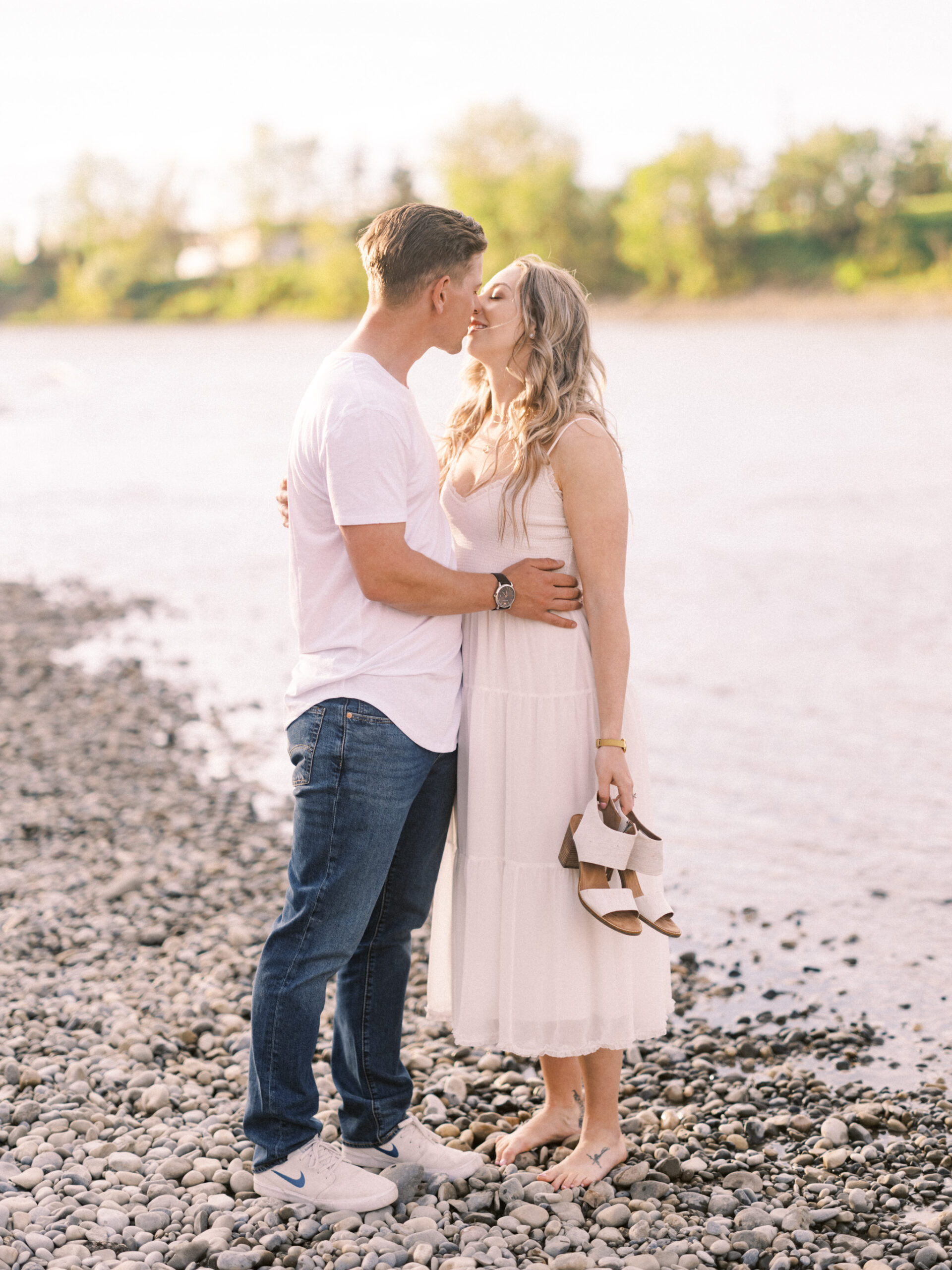 Cherry Blossom Spring Engagement Session, river engagement couple laughing, couple embracing, engagement pose sunset, sunset engagement photos, labrador retriever engagement photos, dog engagement session, puppy engagement session, alberta wedding photographers, alberta photographer, calgary wedding, calgary wedding photographer, spring engagement session, spring photos, nicole sarah, cherry blossom photos, cherry blossom engagement, wedding poses, white dress engagement, sundress white, engagement photos, bow river, puppy engagement photos, neutral engagement photos