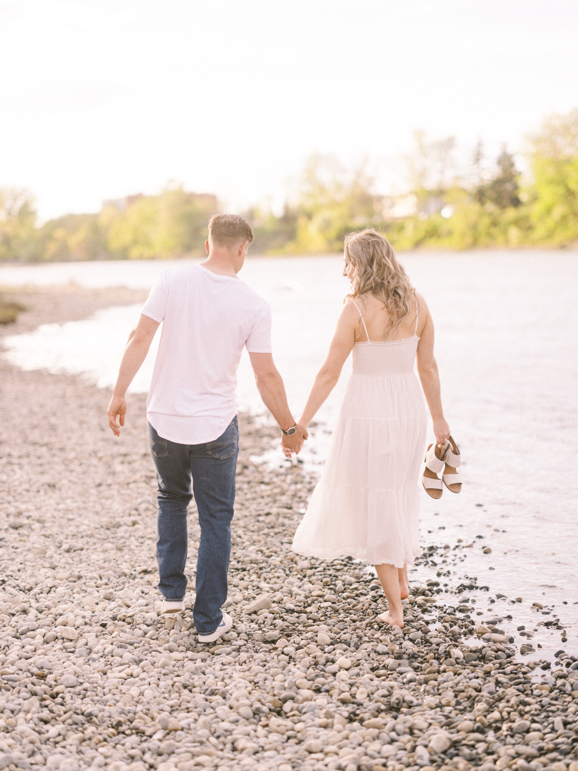 Cherry Blossom Spring Engagement Session, river engagement couple laughing, couple embracing, engagement pose sunset, sunset engagement photos, labrador retriever engagement photos, dog engagement session, puppy engagement session, alberta wedding photographers, alberta photographer, calgary wedding, calgary wedding photographer, spring engagement session, spring photos, nicole sarah, cherry blossom photos, cherry blossom engagement, wedding poses, white dress engagement, sundress white, engagement photos, bow river, puppy engagement photos, neutral engagement photos