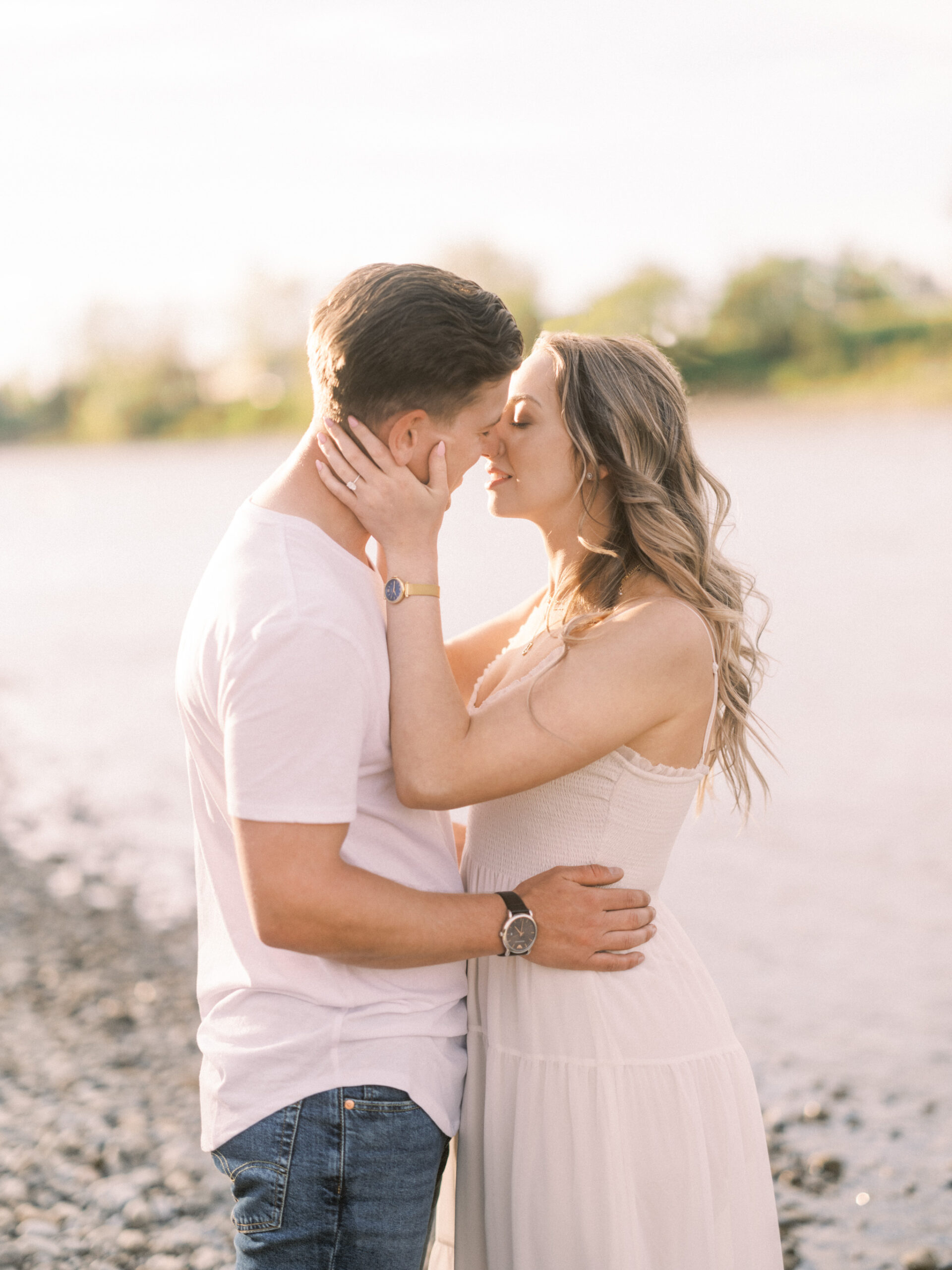 Cherry Blossom Spring Engagement Session, river engagement couple laughing, couple embracing, engagement pose sunset, sunset engagement photos, labrador retriever engagement photos, dog engagement session, puppy engagement session, alberta wedding photographers, alberta photographer, calgary wedding, calgary wedding photographer, spring engagement session, spring photos, nicole sarah, cherry blossom photos, cherry blossom engagement, wedding poses, white dress engagement, sundress white, engagement photos, bow river, puppy engagement photos, neutral engagement photos