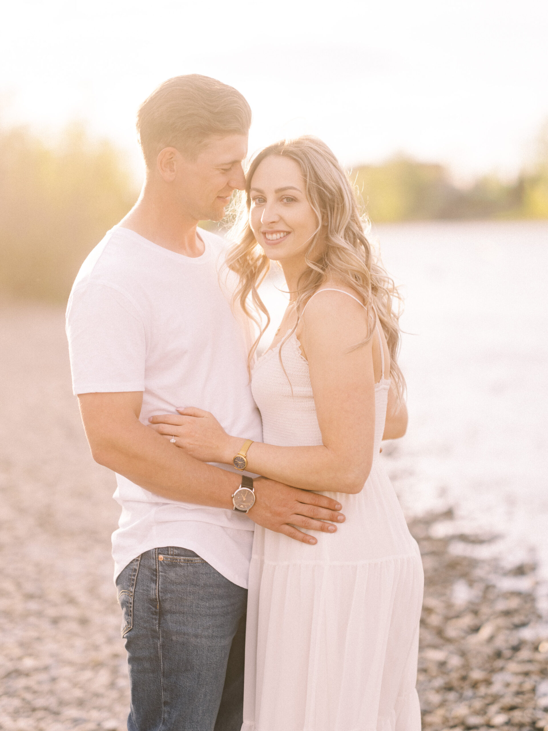 Cherry Blossom Spring Engagement Session, river engagement couple laughing, couple embracing, engagement pose sunset, sunset engagement photos, labrador retriever engagement photos, dog engagement session, puppy engagement session, alberta wedding photographers, alberta photographer, calgary wedding, calgary wedding photographer, spring engagement session, spring photos, nicole sarah, cherry blossom photos, cherry blossom engagement, wedding poses, white dress engagement, sundress white, engagement photos, bow river, puppy engagement photos, neutral engagement photos