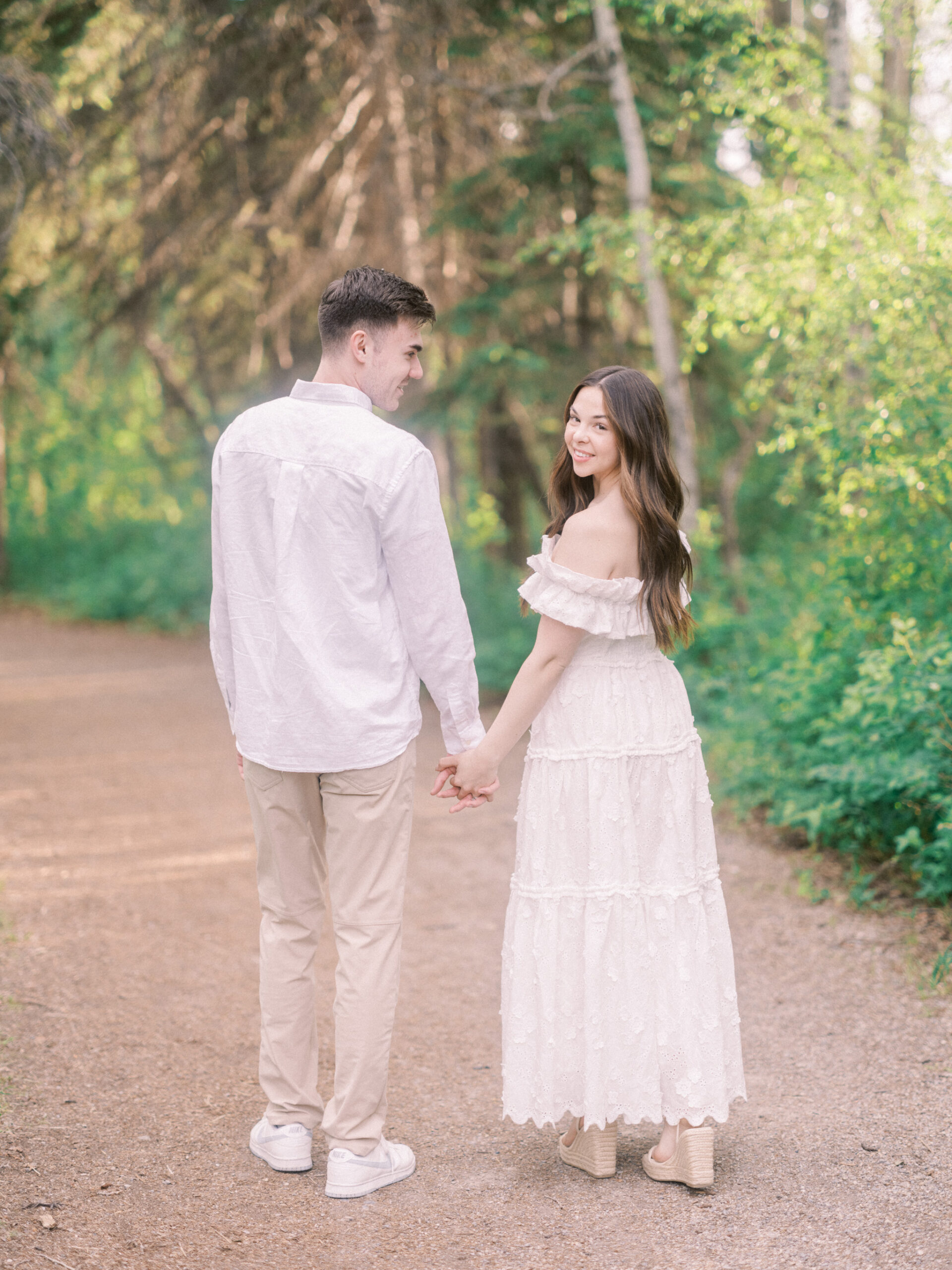 Riverside calgary engagement, forest engagement, bride in white ruffled dress engagement, groom and bride sitting by the river, bride and groom standing in river, standing in sunset forest, nicole sarah, calgary wedding photographers, fish creek park engagement