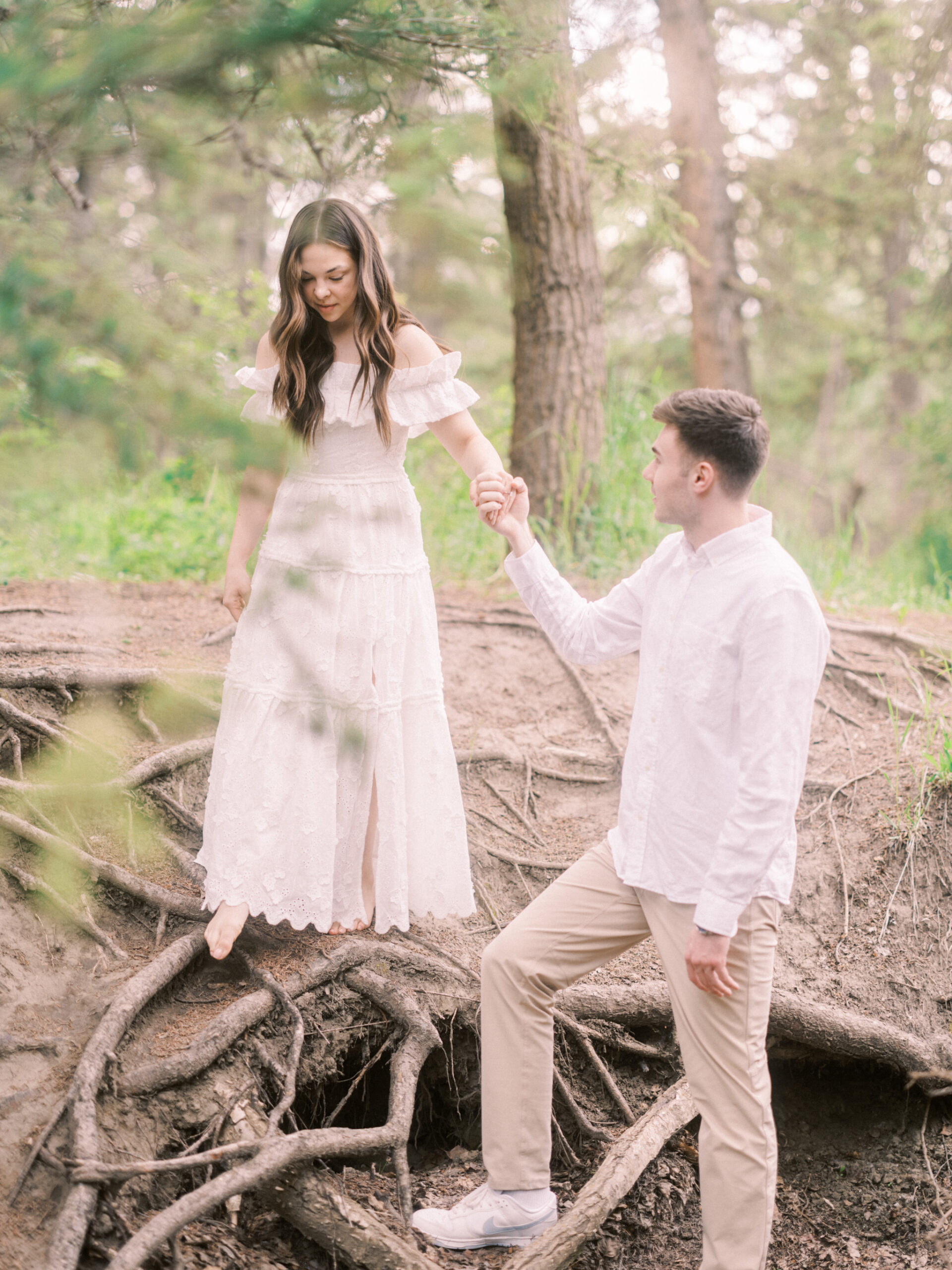 Riverside calgary engagement, forest engagement, bride in white ruffled dress engagement, groom and bride sitting by the river, bride and groom standing in river, standing in sunset forest, nicole sarah, calgary wedding photographers, fish creek park engagement