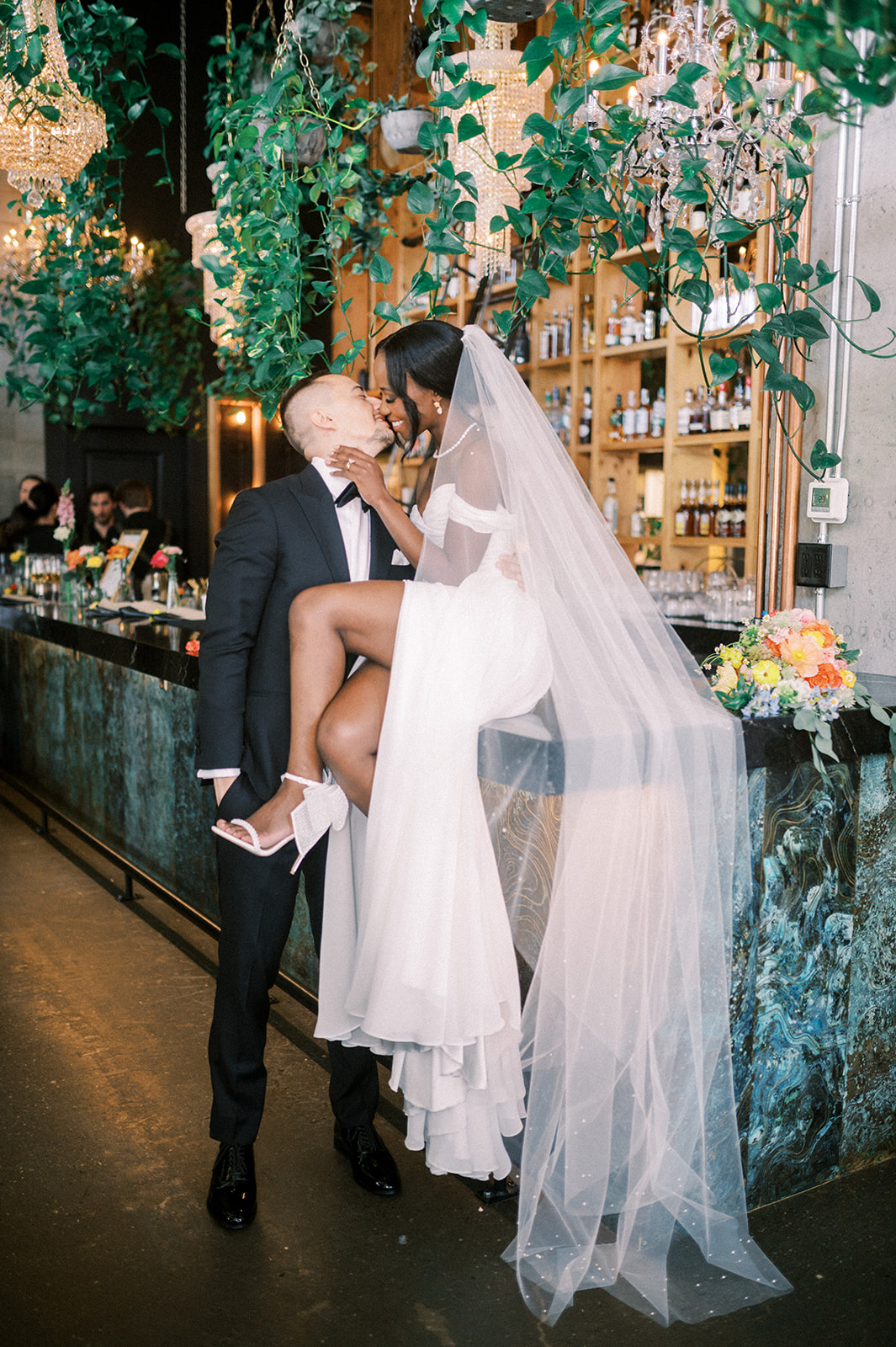 bride sitting on bar kissing groom, bride with legs crossed on bar, fun wedding bar photo, fun wedding reception pose, calgary photographers wedding, fun wedding photos, The Ultimate Calgary Wedding Photography Guide: Everything You Need to Know Before Your Wedding